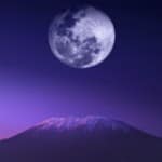 Climbers trekking Mount Kilimanjaro in clear weather with views of Kibo Peak and alpine landscape